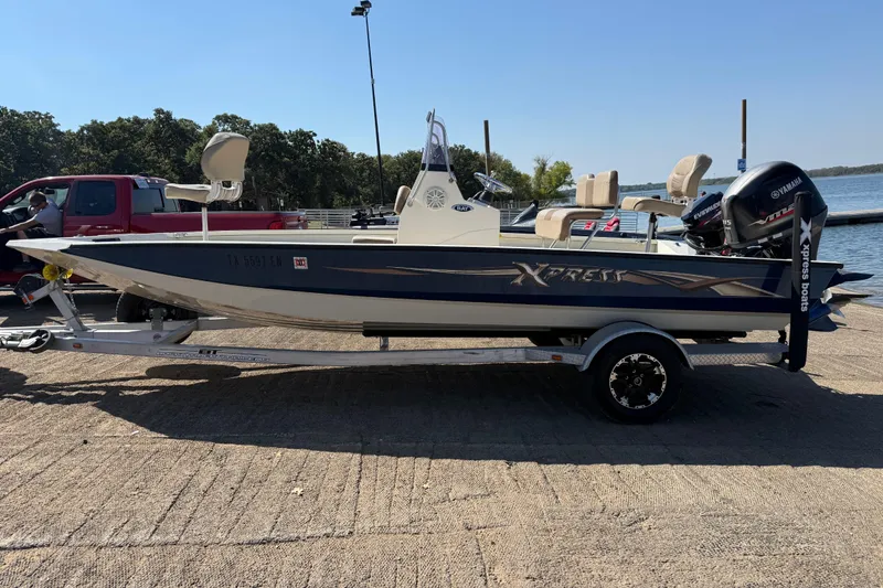 Slide: The Image of 2018 Xpress H20B Bay boat on trailer by the water, featuring Yamaha outboard motor. - 33