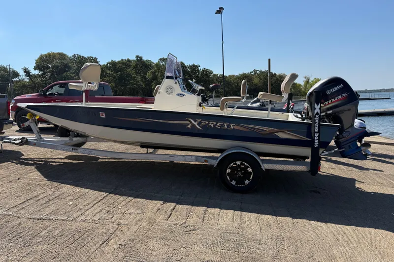 Slide: The Image of 2018 Xpress H20B Bay boat on trailer with Yamaha outboard motor at lakeside. - 34