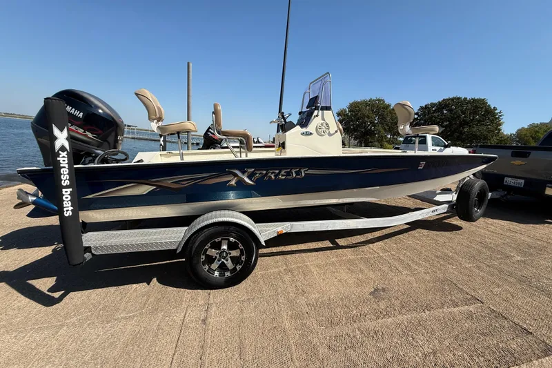 Slide: The Image of 2018 Xpress H20B Bay boat on trailer, parked near water. - 44