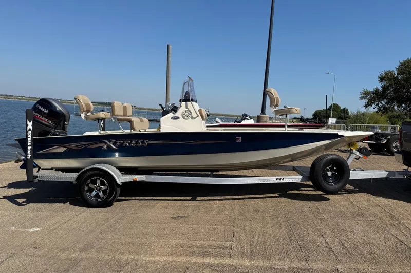 Slide: The Image of 2018 Xpress H20B Bay boat on trailer by the water, featuring Yamaha outboard motor. - 47