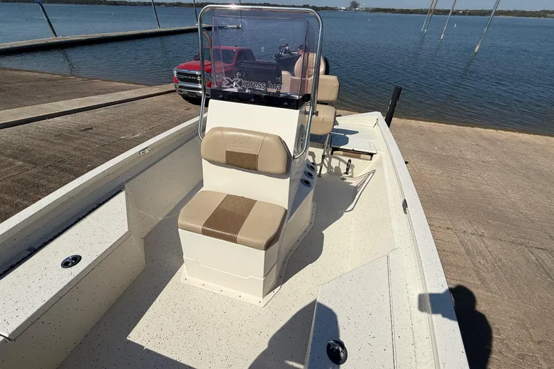 Slide: The Image of 2018 Xpress H20B Bay boat at dock, featuring beige seating and console. - 51