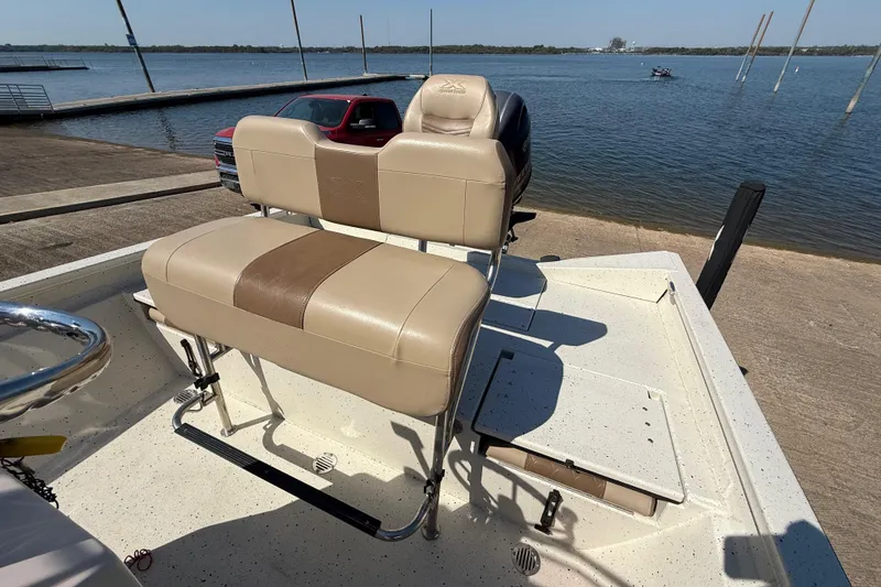 Slide: The Image of 2018 Xpress H20B Bay boat with tan seating, docked by a serene waterfront. - 58