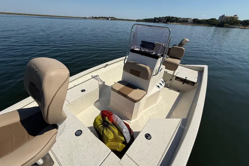 Slide: The Image of 2018 Xpress H20B Bay boat on calm water, featuring beige seating and console. - 77