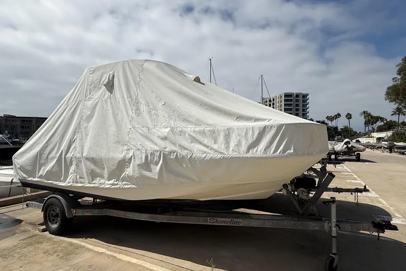 Slide: The Image of 2019 Boston Whaler 190 Montauk boat with outboard motor, parked outdoors near palm trees. - 10
