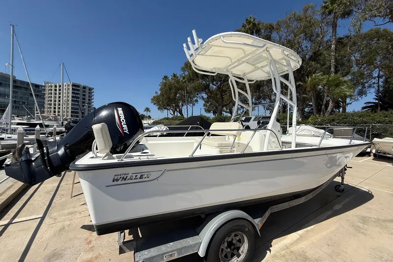 Slide: The Image of 2019 Boston Whaler 190 Montauk boat docked in a marina with clear blue water. - 2