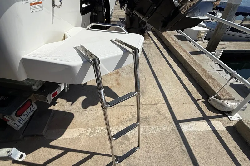 Slide: The Image of 2019 Boston Whaler 190 Montauk boat on trailer, docked with trees and buildings in background. - 6