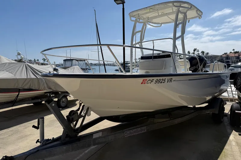 Slide: The Image of 2019 Boston Whaler 190 Montauk boat on trailer, docked under clear blue sky. - 7
