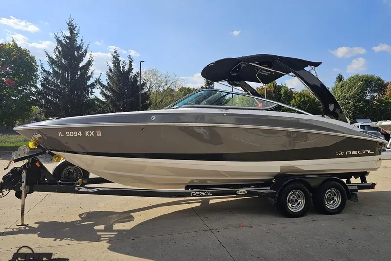 Slide: The Image of 2018 Regal 2500 Bowrider boat on trailer, parked outdoors under clear sky. - 21