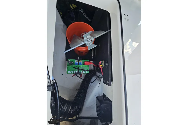 Slide: The Image of 2018 Regal 2500 Bowrider storage compartment with battery, propeller, and orange bucket. - 44