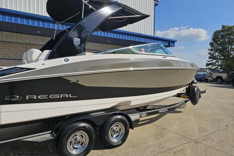 Slide: The Image of 2018 Regal 2500 Bowrider boat on trailer, parked outdoors under blue sky. - 9