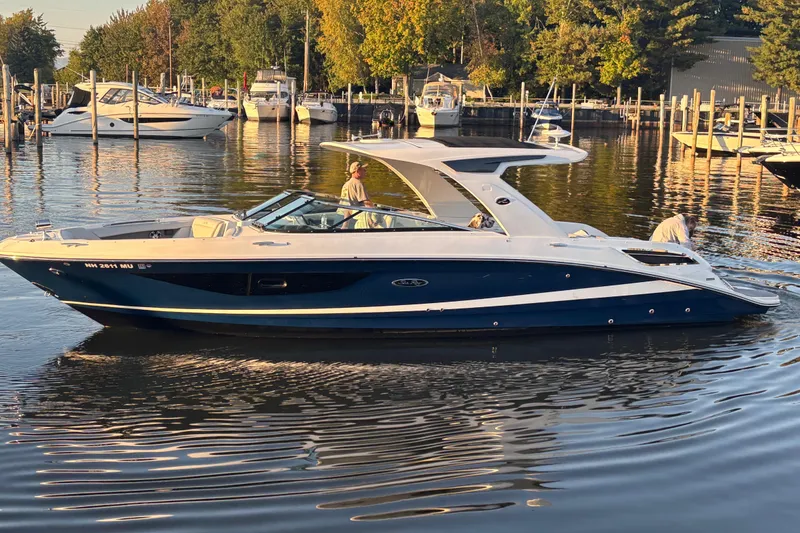 Slide: The Image of 2022 Searay SLX350 boat docked in a marina with calm water and trees. - 1