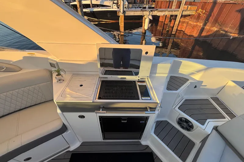 Slide: The Image of 2022 Searay SLX350 boat interior with grill and seating area by the water. - 14