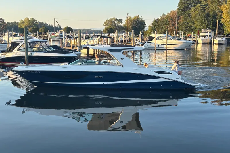 Slide: The Image of 2022 Searay SLX350 boat cruising in a marina, surrounded by other boats and calm water. - 2