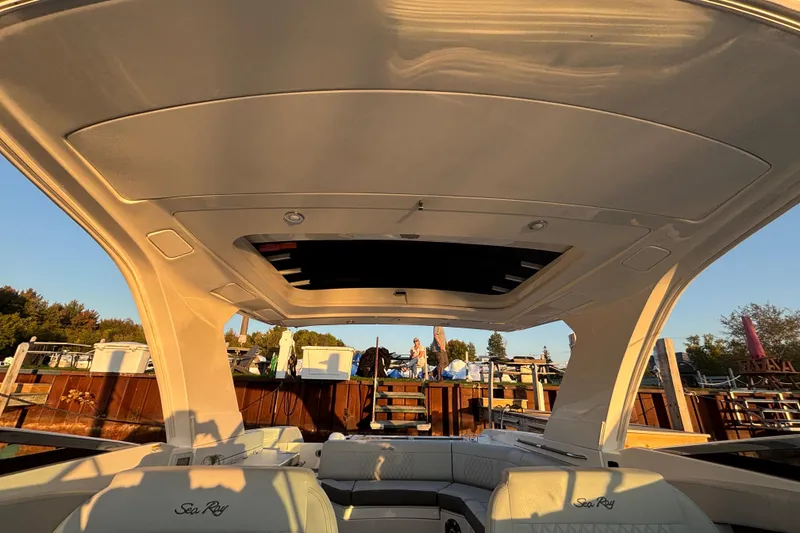 Slide: The Image of 2022 Searay SLX350 boat interior with open sunroof, docked at marina. - 24