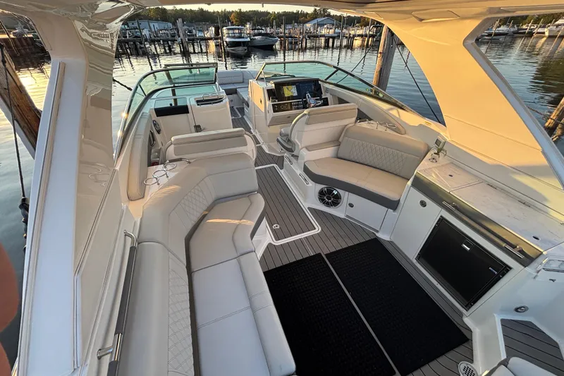 Slide: The Image of Luxurious 2022 Searay SLX350 boat interior with plush seating and modern amenities at a marina. - 26
