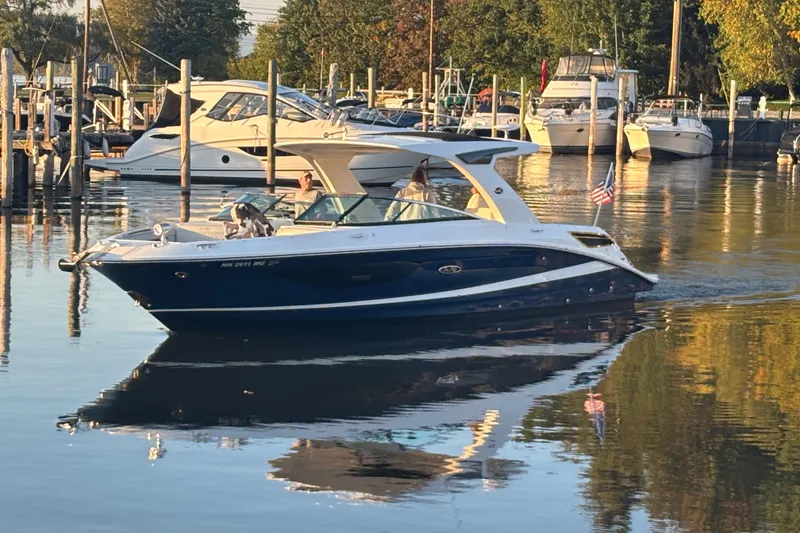 Slide: The Image of 2022 Searay SLX350 boat cruising in a marina, surrounded by other docked boats. - 4
