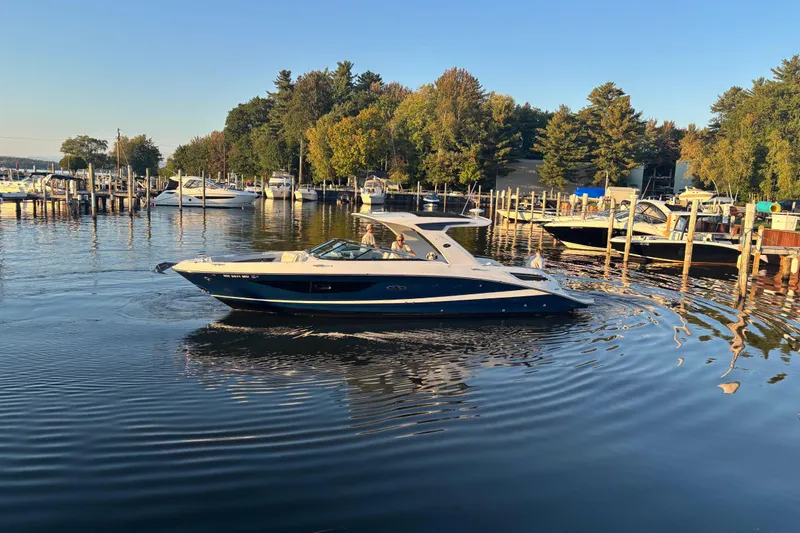 Slide: The Image of 2022 Searay SLX350 boat cruising in a scenic marina with surrounding trees. - 5