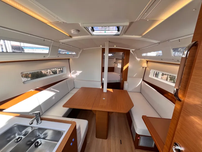 Slide: The Image of 2024 Jeanneau 380 yacht interior with modern seating, dining table, and kitchenette. - 15