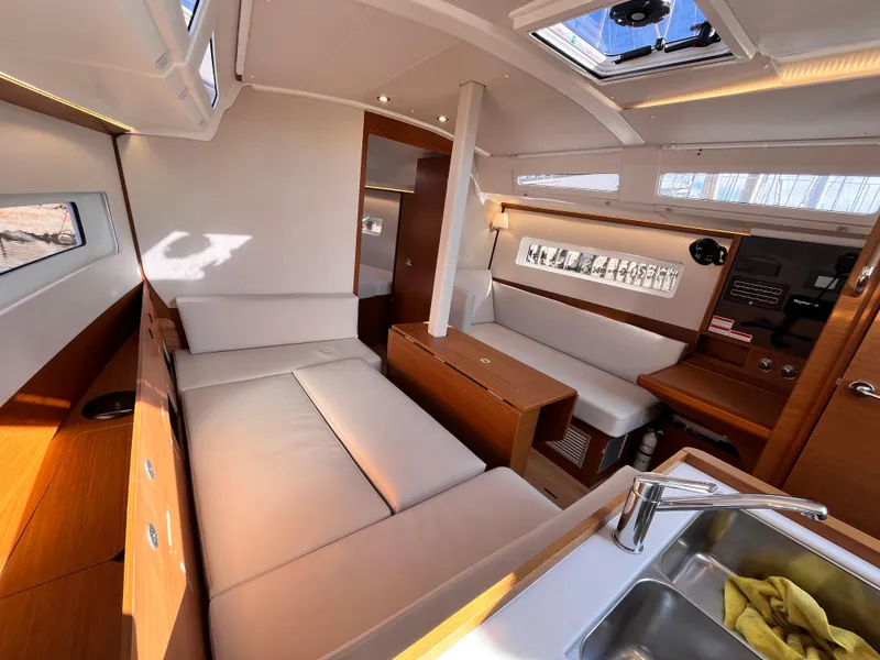 Slide: The Image of 2024 Jeanneau 380 yacht interior with modern seating, wood finishes, and skylight. - 20