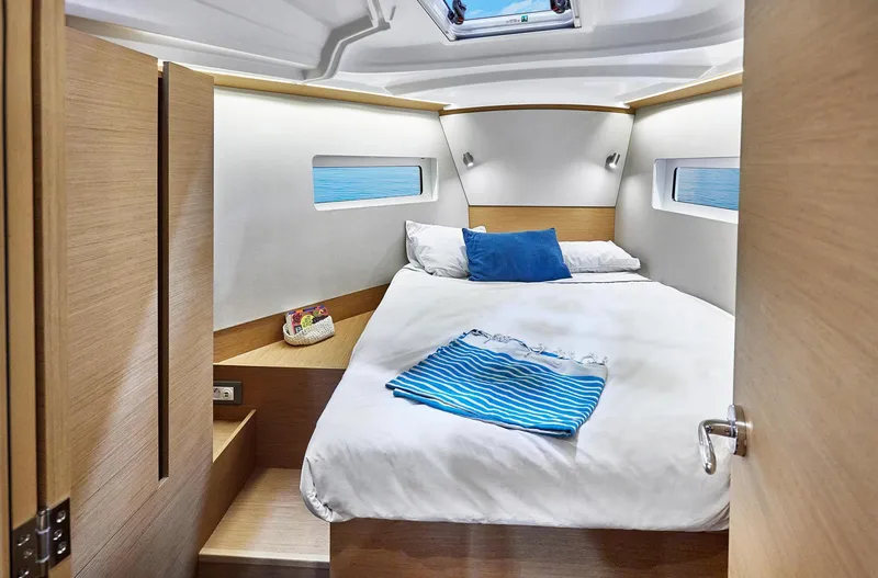 Slide: The Image of 2024 Jeanneau 380 yacht cabin with cozy bed, modern design, and natural light. - 25