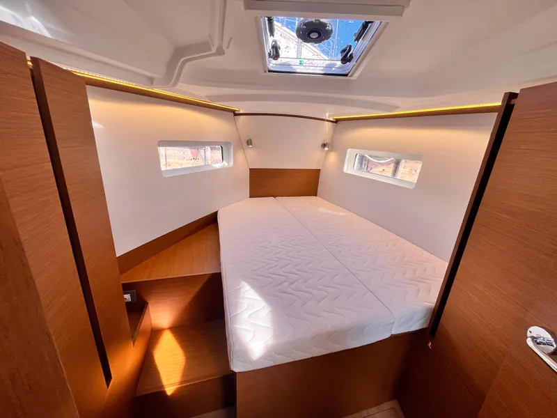 Slide: The Image of 2024 Jeanneau 380 cabin interior with double bed, wooden finish, and natural light. - 26