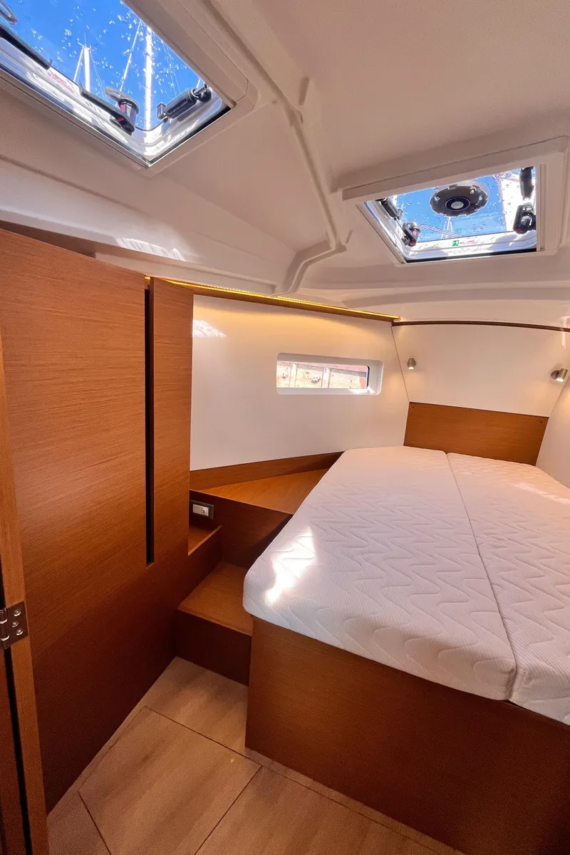 Slide: The Image of 2024 Jeanneau 380 cabin interior with skylights, wooden finish, and comfortable bedding. - 29