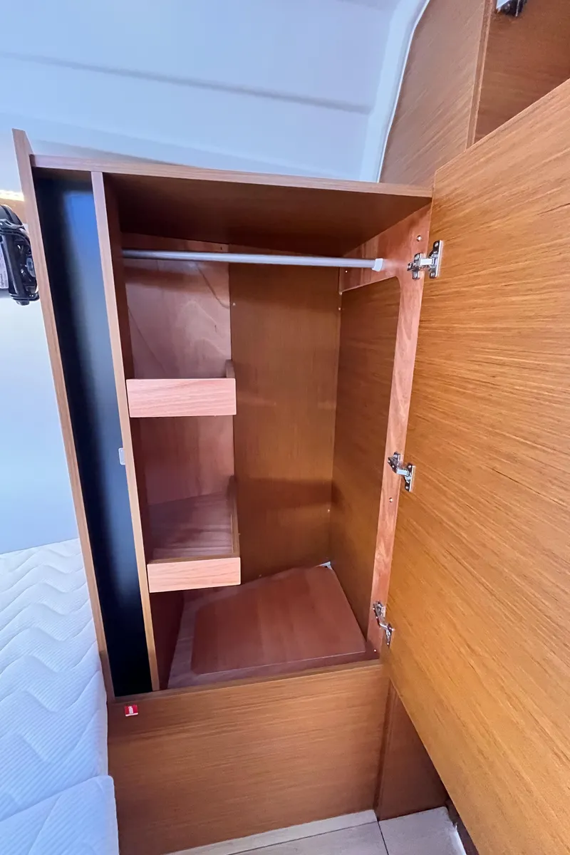 Slide: The Image of 2024 Jeanneau 380 interior wooden cabinet with shelves and hanging rod. - 34