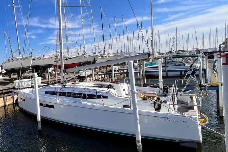 Slide: The Image of 2024 Jeanneau 380 sailboat docked in marina, clear blue sky, multiple sailboats in background. - 4