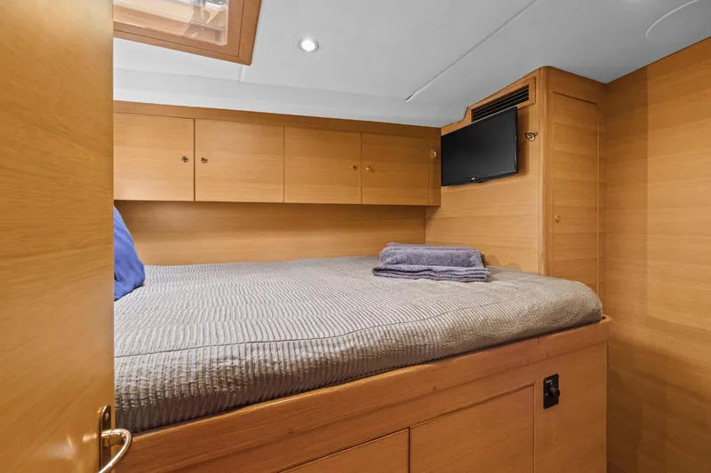 Slide: The Image of Cozy cabin interior of 2013 Hylas 63 yacht with bed, TV, and wooden cabinetry. - 59