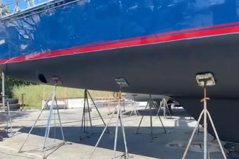 Slide: The Image of 2013 Hylas 63 yacht on stands, blue hull with red stripe, in dry dock. - 80