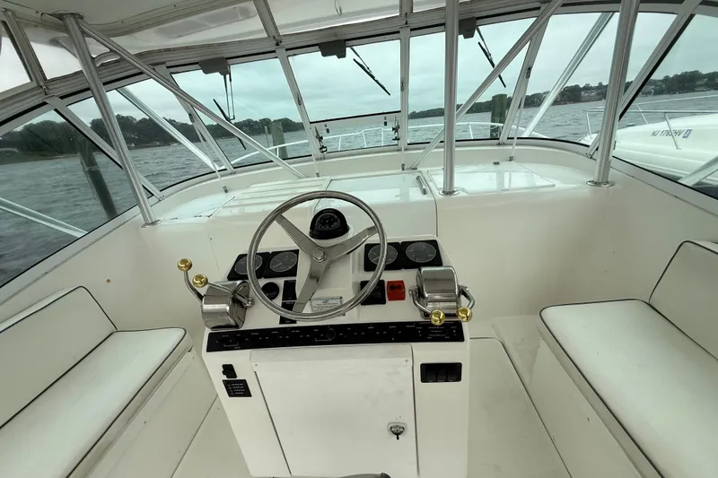 Slide: The Image of 2003 Luhrs 32 Open boat helm with steering wheel and controls, on a calm water backdrop. - 7