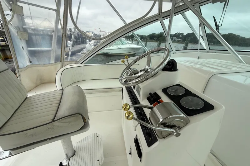 Slide: The Image of 2003 Luhrs 32 Open boat helm with steering wheel and controls, docked by the water. - 8