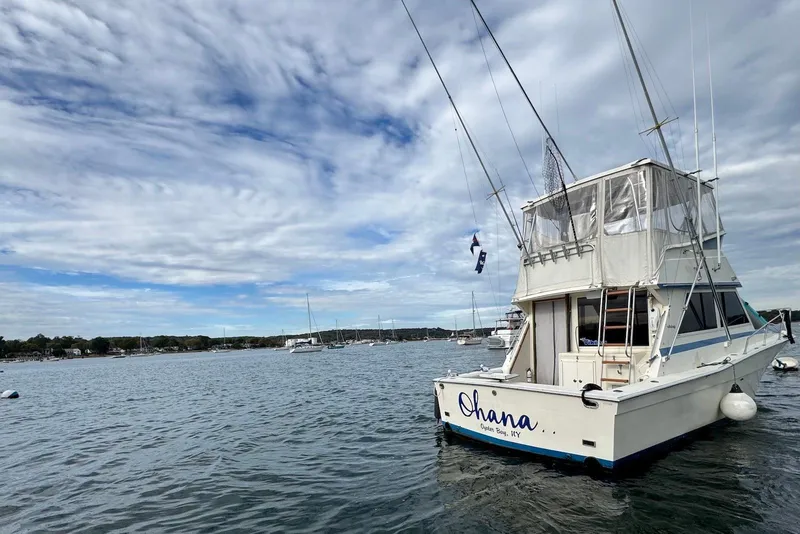 Slide: The Image of 1986 Viking 35 Convertible boat named "Ohana" on calm water under cloudy sky. - 5