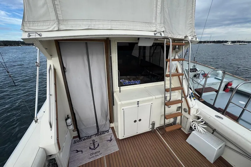 Slide: The Image of 1986 Viking 35 Convertible yacht deck with ladder and welcome mat, docked on calm water. - 6