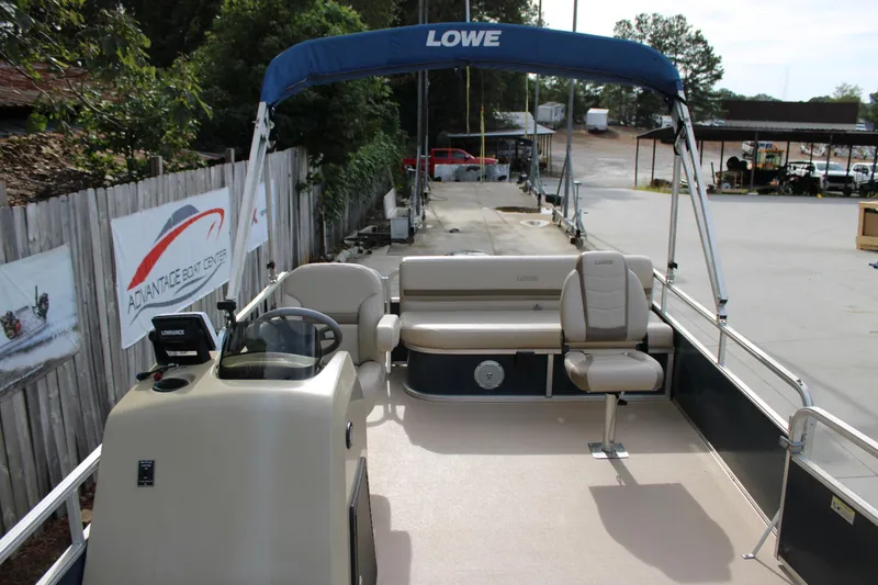 Slide: The Image of 2016 Lowe Ultra 182 Fish & Cruise pontoon boat with canopy and seating, docked at a boat center. - 17