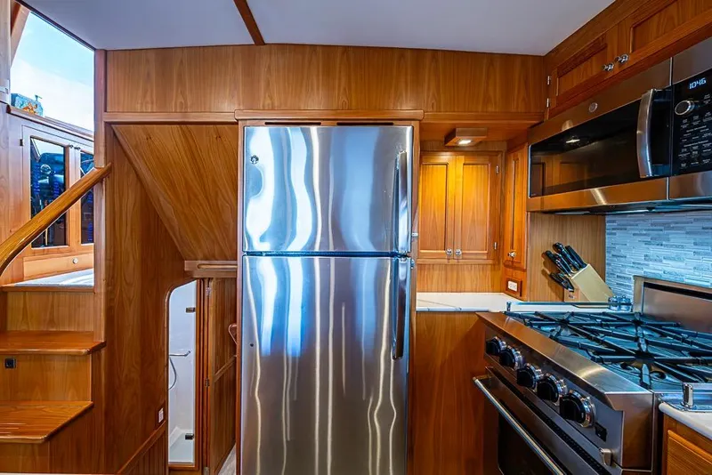 Slide: The Image of 2019 Kadey-Krogen 44 AE yacht kitchen with stainless steel appliances and wooden cabinetry. - 19