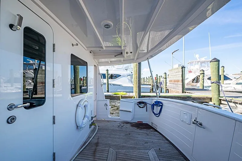 Slide: The Image of 2019 Kadey-Krogen 44 AE yacht deck with wooden flooring and marina view. - 46