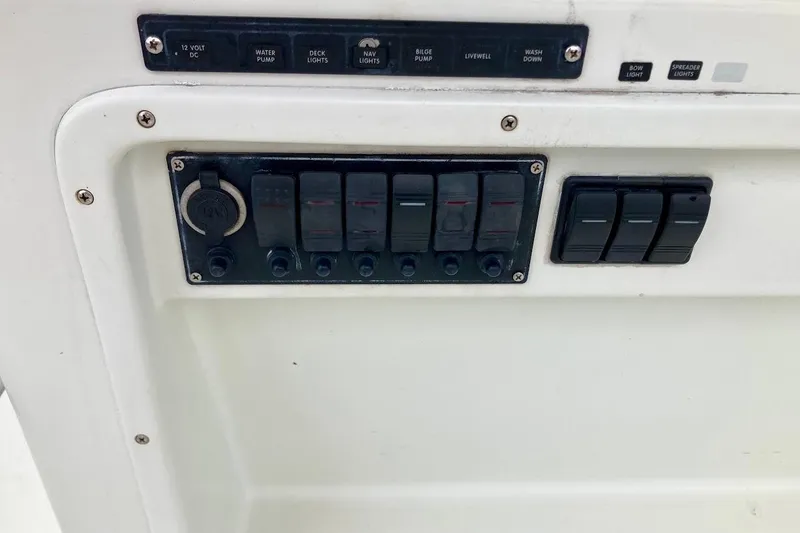 Slide: The Image of Control panel of a 2007 Action Craft Coastal Bay 2310 boat with various switches. - 19