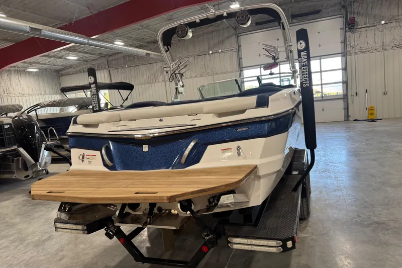 Slide: The Image of 2019 MasterCraft XT25 boat in showroom, rear view with wooden swim platform. - 11