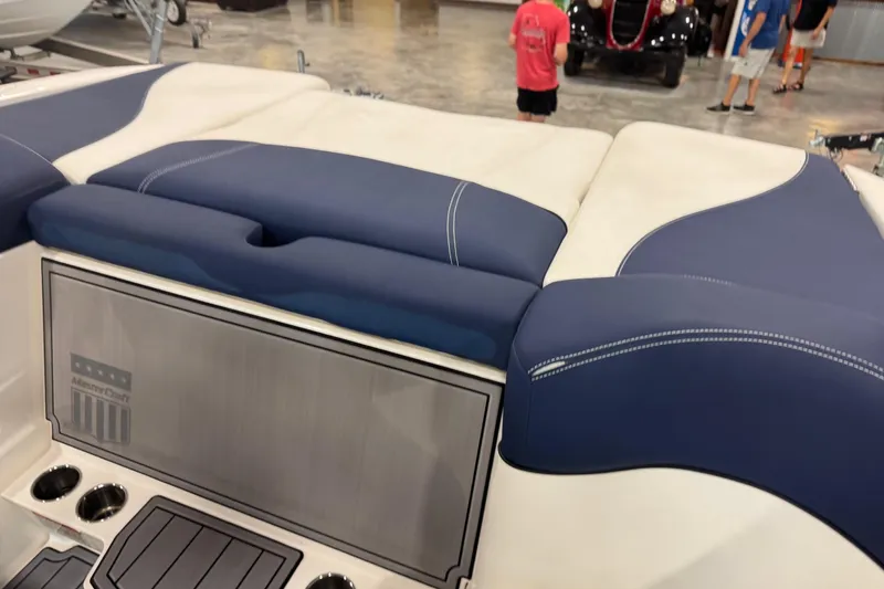 Slide: The Image of 2019 MasterCraft XT25 boat interior with blue and white seating, cup holders, and storage compartment. - 9