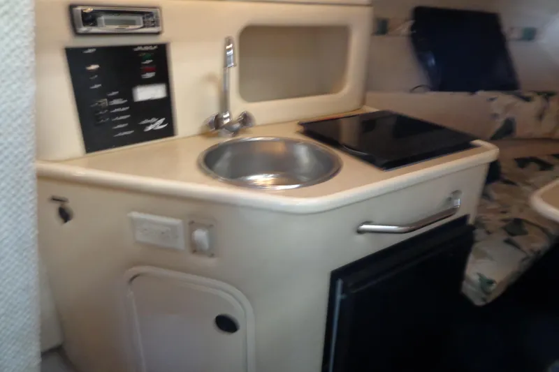 Slide: The Image of Compact kitchenette in a 2000 Sea Ray 240 Sundancer boat, featuring sink and stove. - 15
