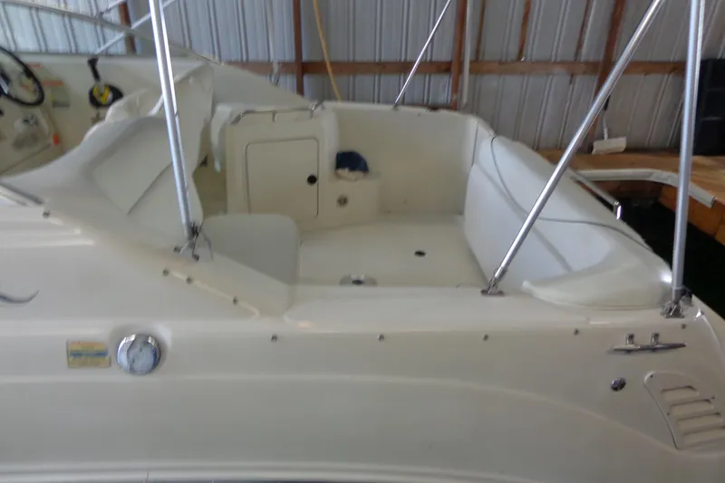 Slide: The Image of 2000 Sea Ray 240 Sundancer boat interior with white seating in a docked position. - 4