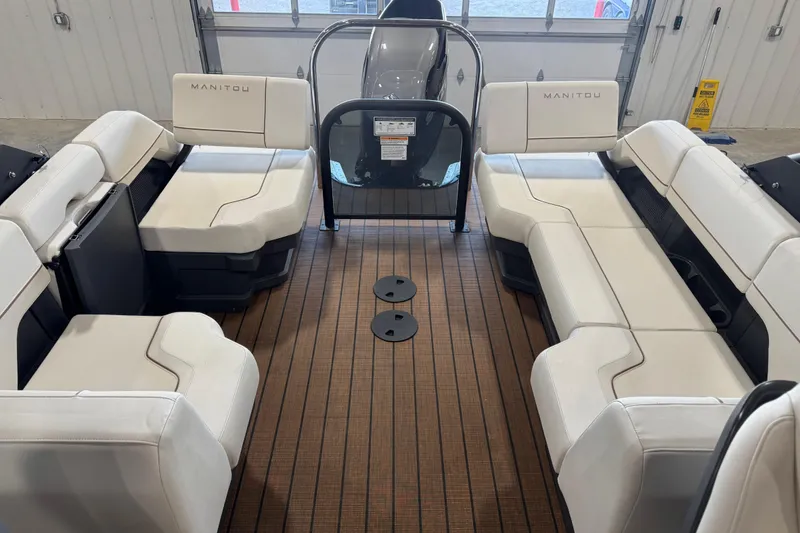 Slide: The Image of 2025 Manitou 26 Explore boat interior with white seating and wood-style flooring. - 11