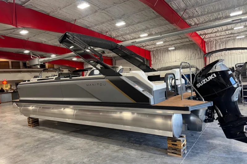 Slide: The Image of 2025 Manitou 26 Explore pontoon boat with Suzuki engine in a showroom. - 3