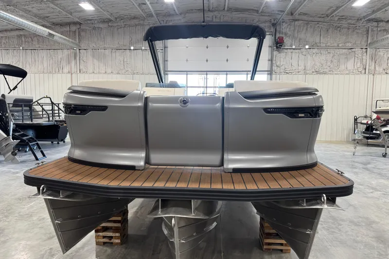 Slide: The Image of 2025 Manitou 26 Explore pontoon boat in a showroom, featuring sleek design and wooden deck. - 5
