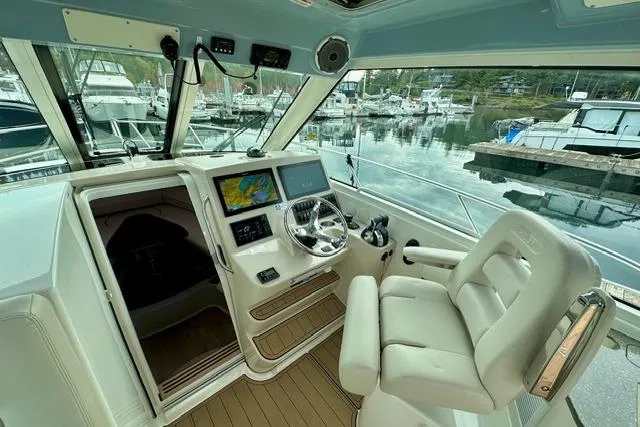 Slide: The Image of 2021 Boston Whaler 345 Conquest Pilothouse interior with helm, navigation screens, and marina view. - 39