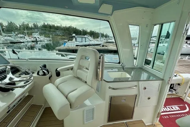 Slide: The Image of 2021 Boston Whaler 345 Conquest Pilothouse interior with helm, seating, and marina view. - 40