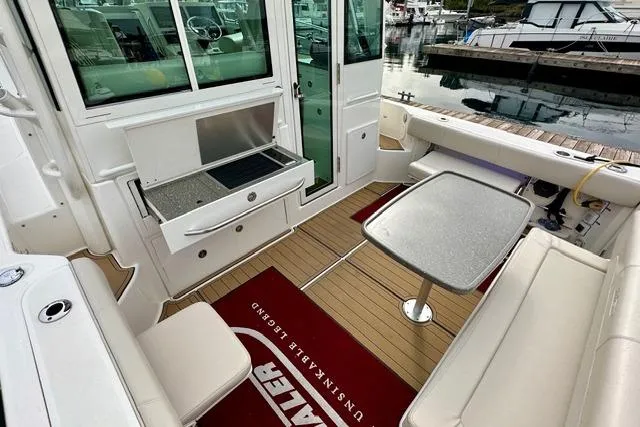 Slide: The Image of 2021 Boston Whaler 345 Conquest Pilothouse interior with seating, table, and grill. - 9