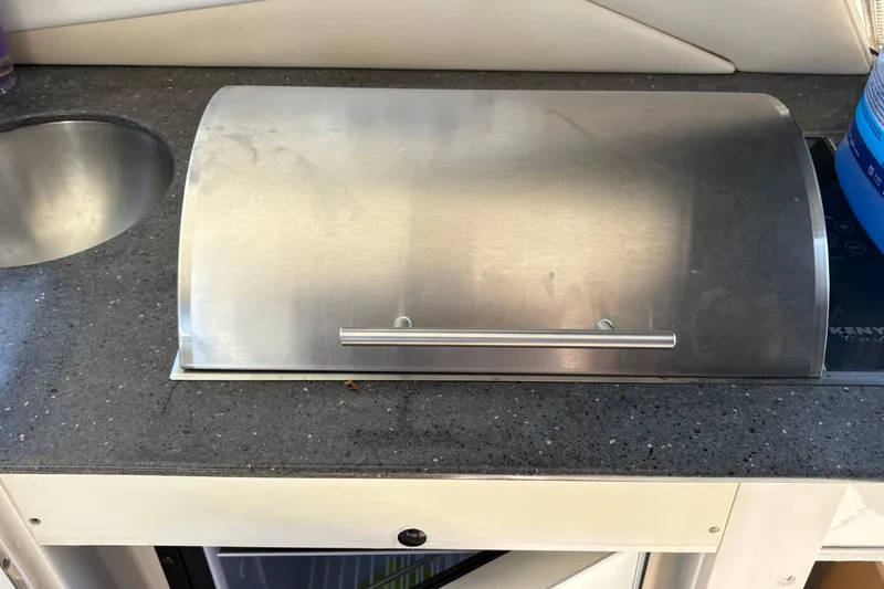 Slide: The Image of 2012 Sea Ray 370 Sundancer kitchen area with open cabinet and trash bin. - 22