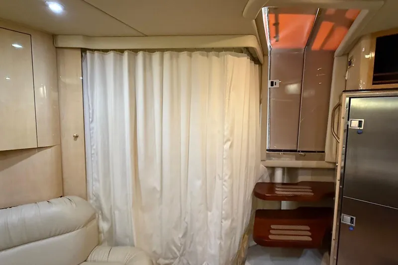 Slide: The Image of Interior of 2000 Sea Ray 380 Sundancer with curtain, shelves, and stainless steel fridge. - 19